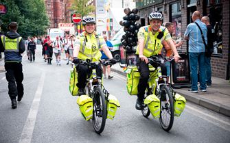 Two Emergency Cycle Responders cycling down the street during a festival