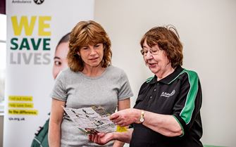 First Aid Community Advocate sharing a pocket first aid guide with a member of the public.
