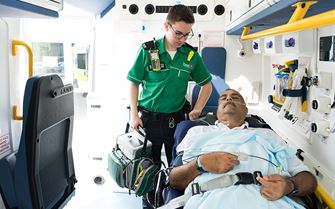 Ambulance staff checking on a patient on a stretcher inside an ambulance. 